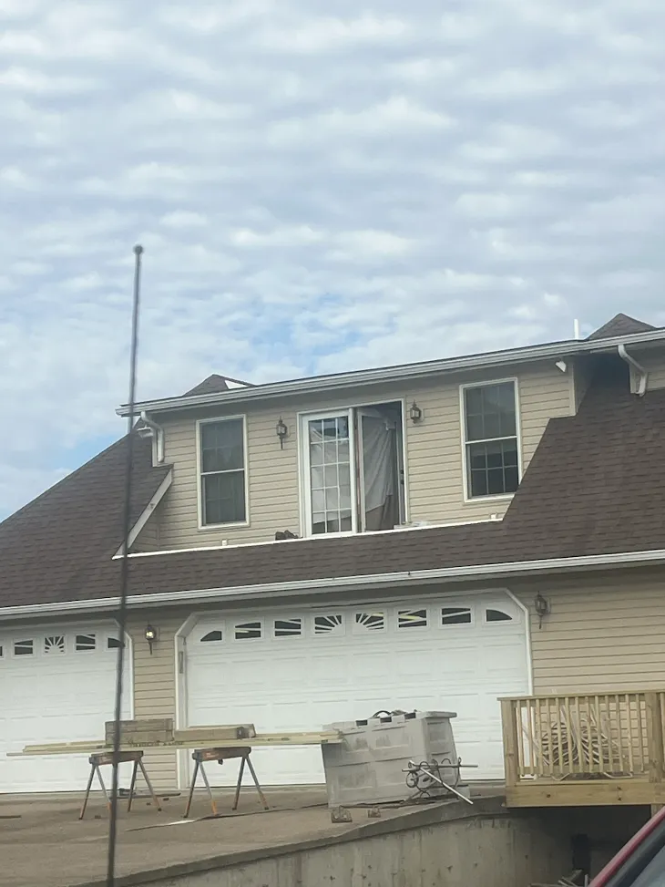 Dormer above a garage with a sliding glass door and flanking windows during a balcony remodel