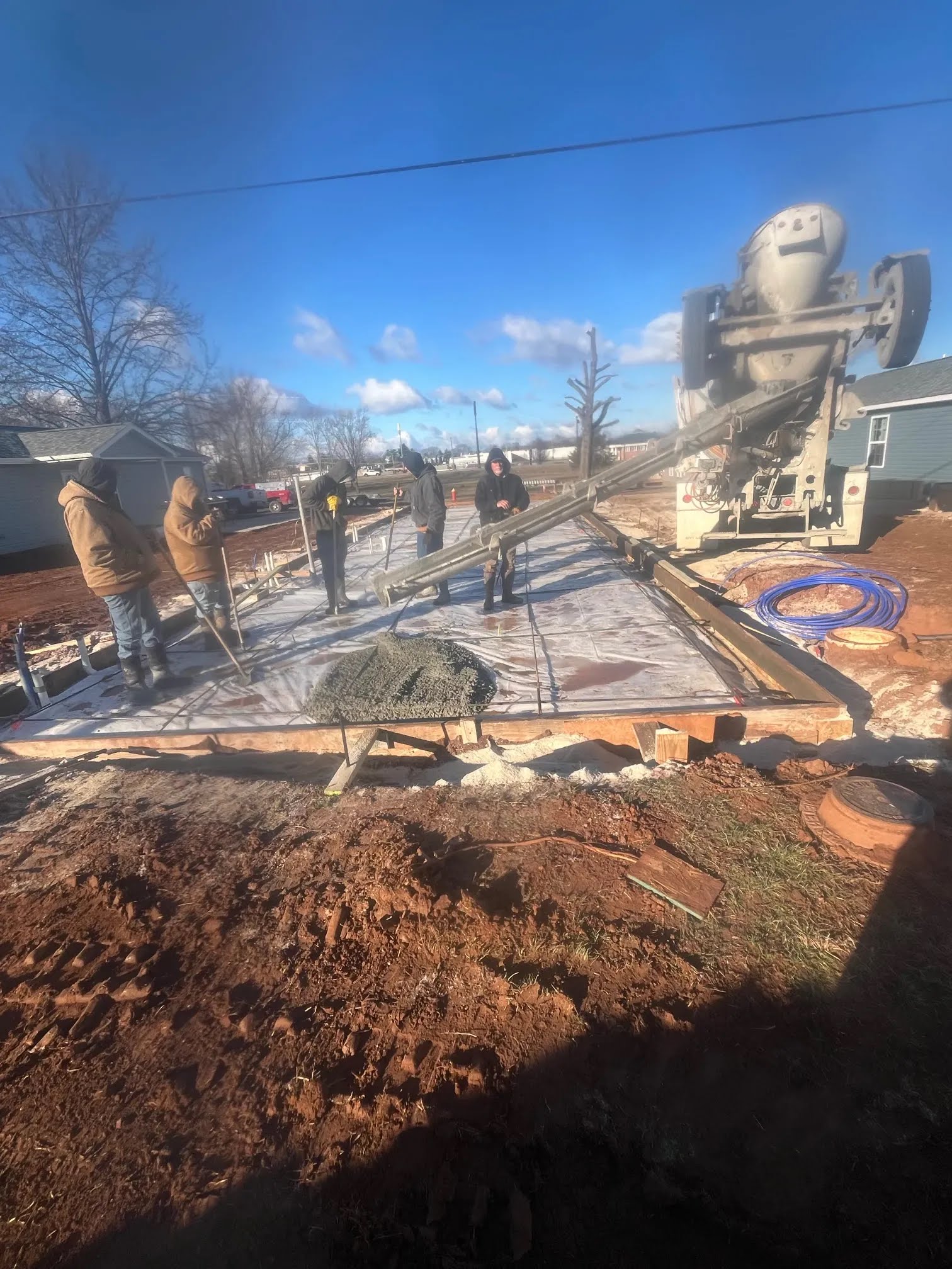 Crew standing on a prepared slab form as a concrete mixer truck pours
