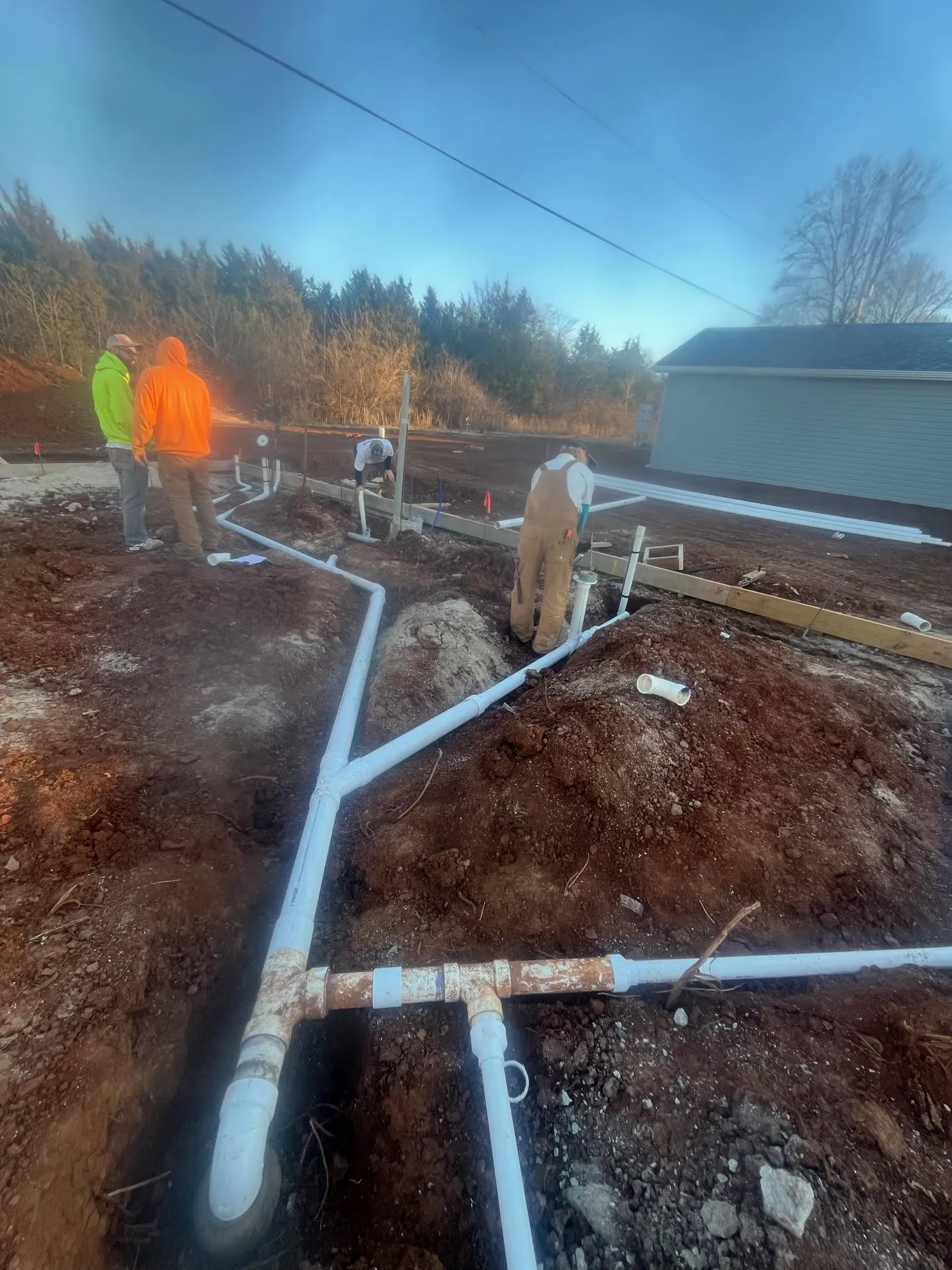 White plumbing pipes laid in trenches before the slab is poured