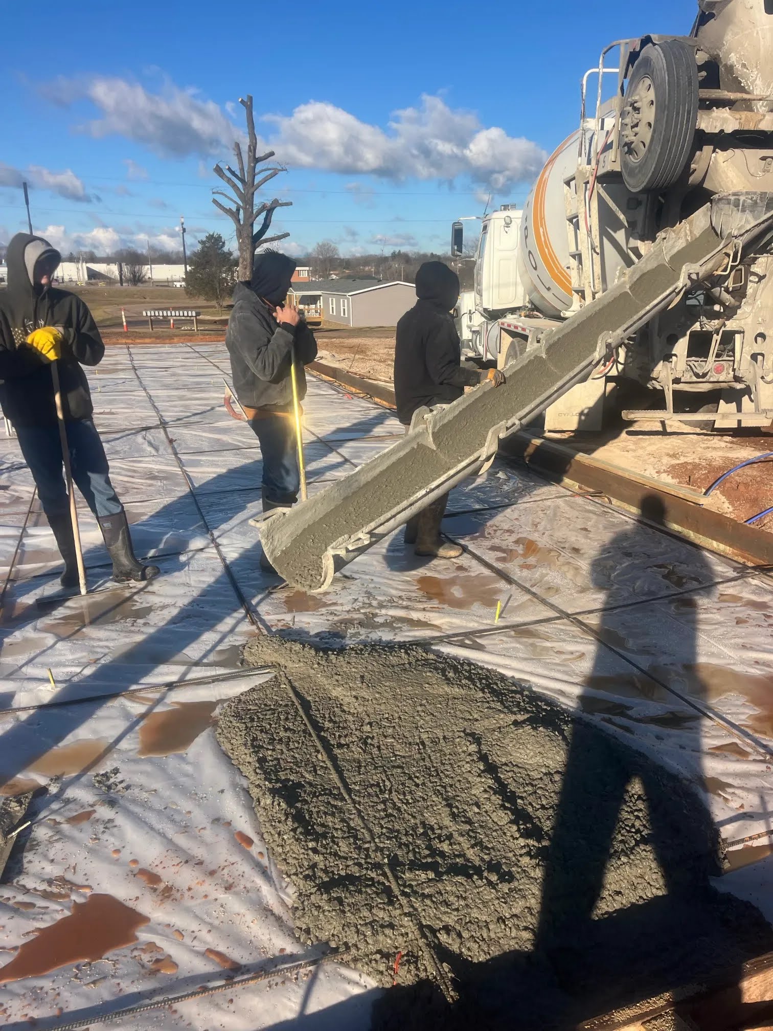 Concrete flowing from a mixer chute onto a prepared slab with rebar