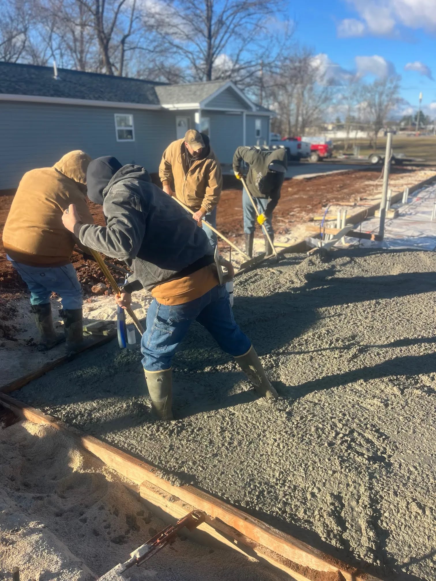 Crew spreading and leveling freshly poured concrete in wood forms
