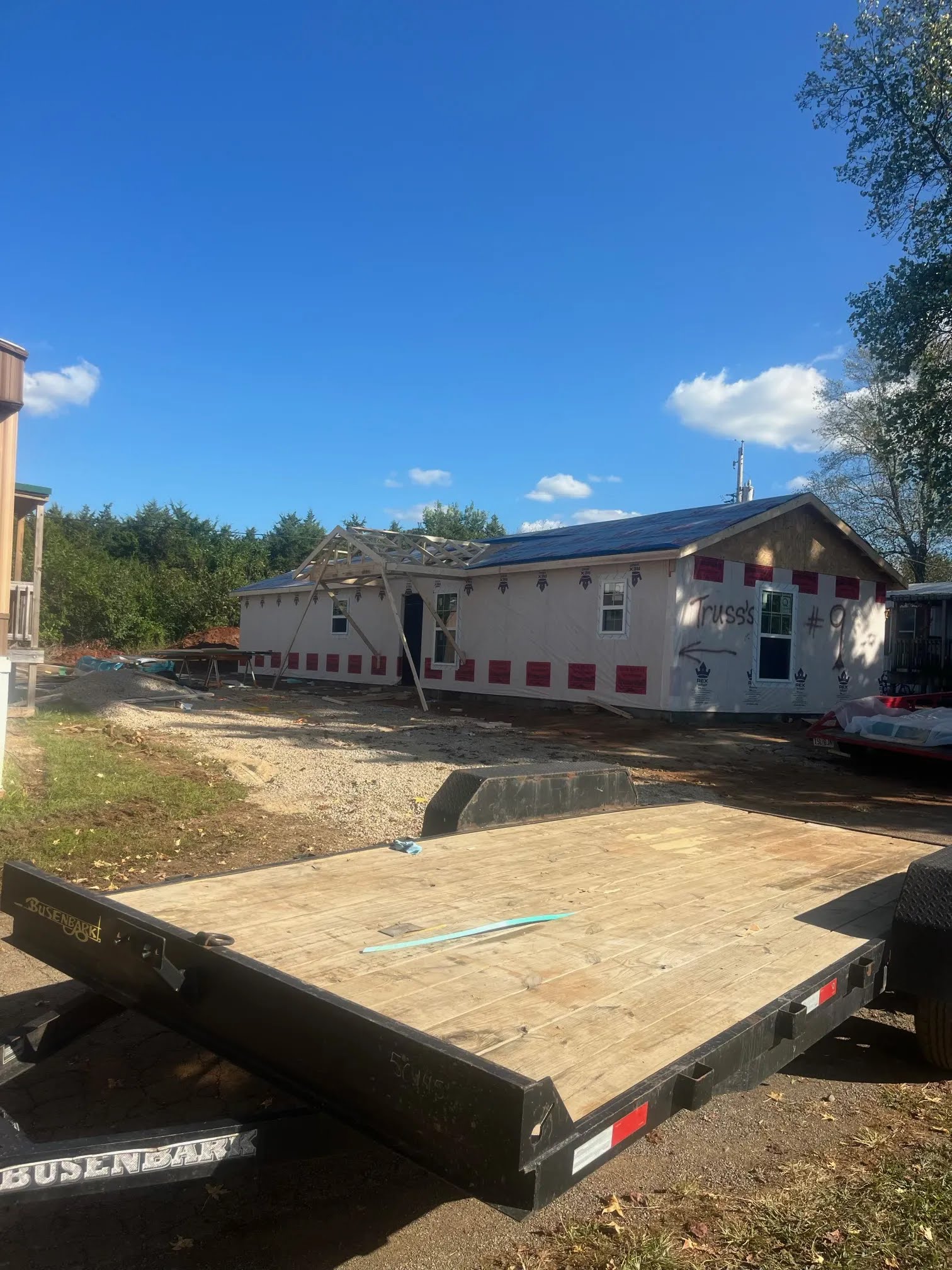 House under construction with house wrap, windows, and porch framing started