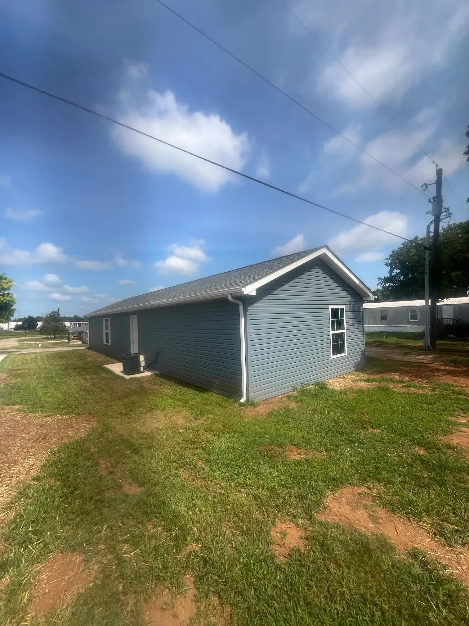 Rear corner of a blue home with white downspout, windows, and siding