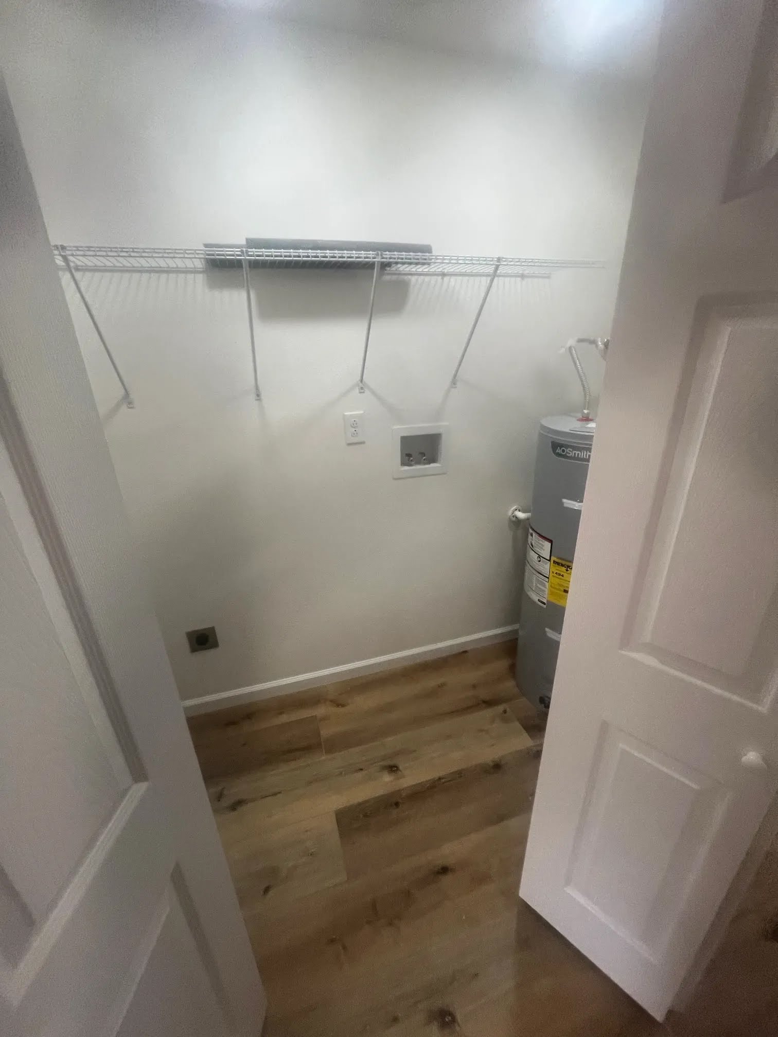 Utility closet with wire shelving, washer hookups, and a water heater