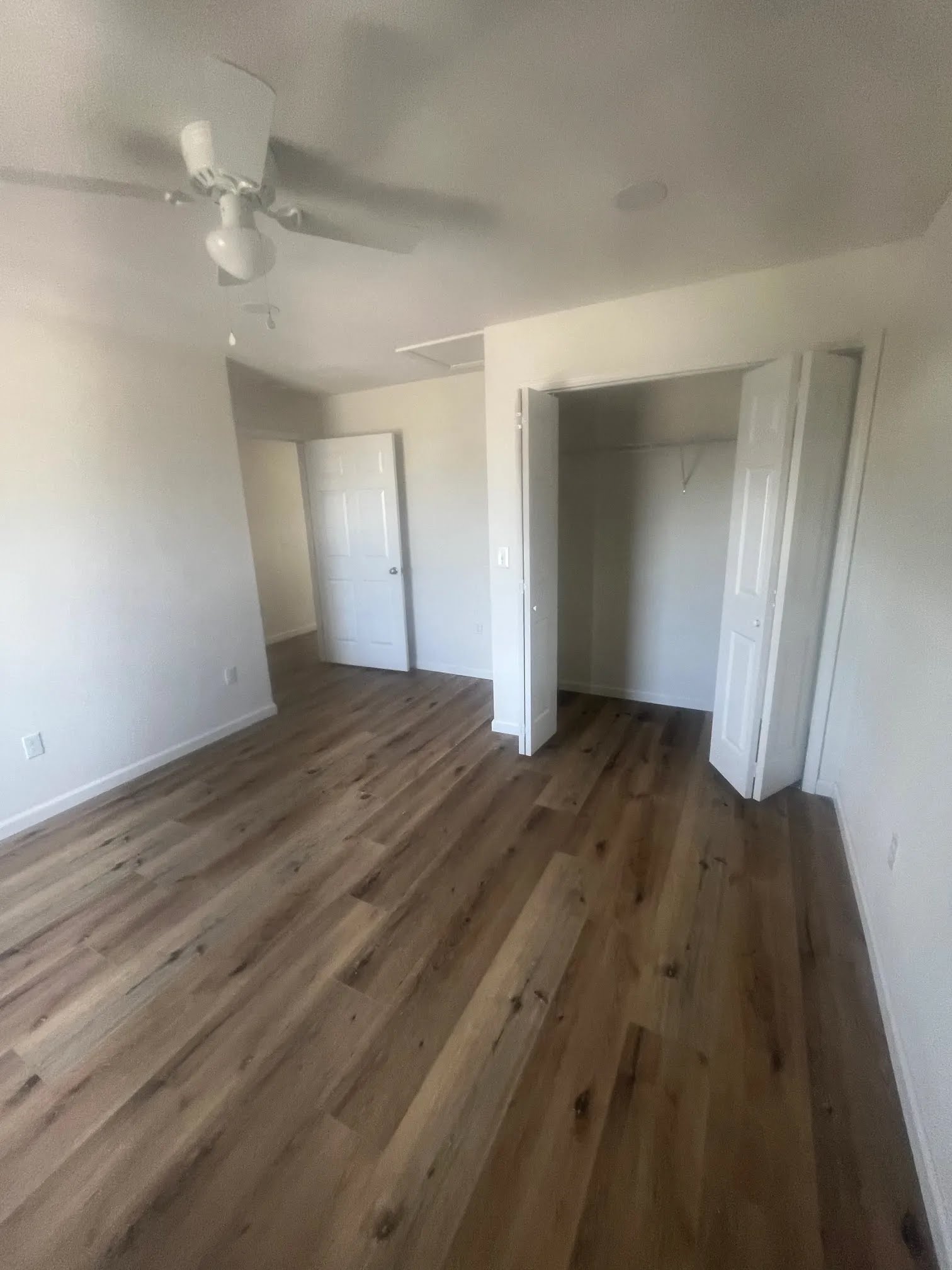 Bedroom with a ceiling fan, closet opening, and wood-look flooring