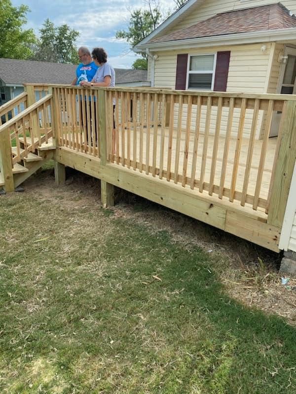 Raised wooden deck with stairs attached to a home with cream siding
